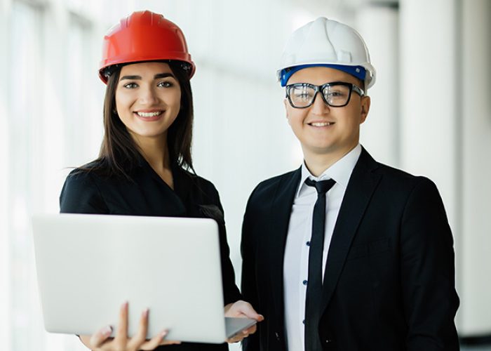 Engineers working on a building site holding a laptop, architect man working with engineer woman inspection in workplace for architectural plan